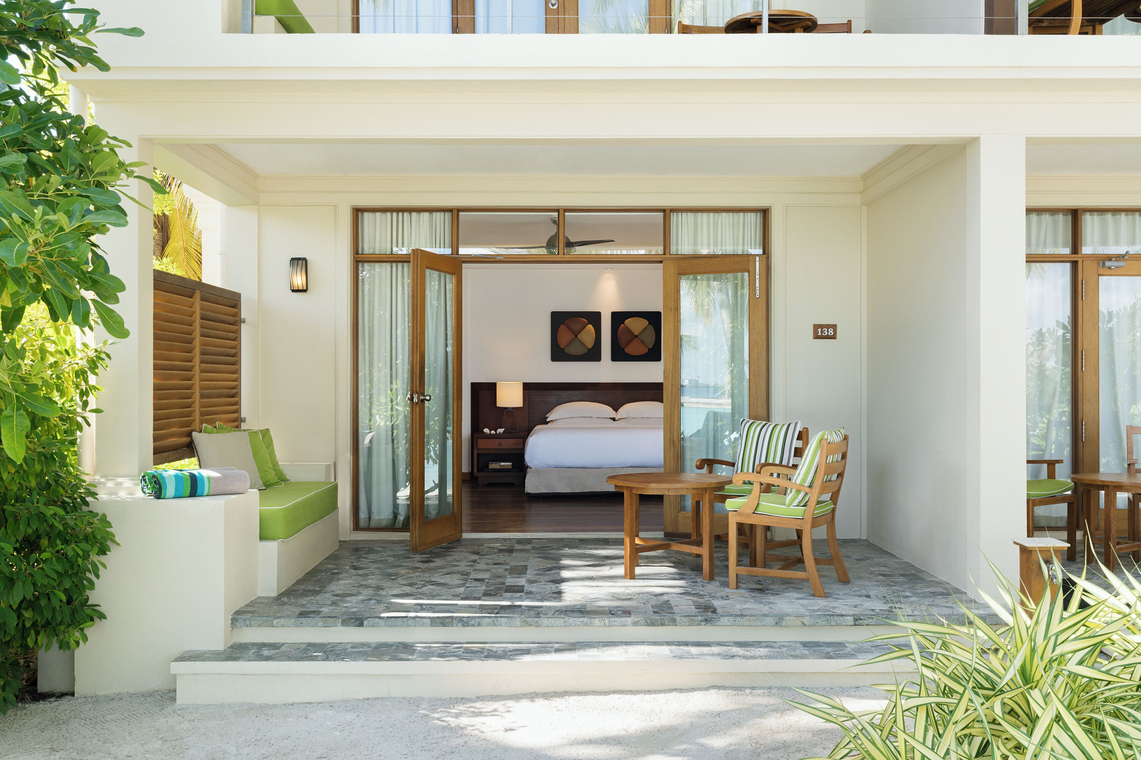 L’entrée d’un hôtel avec un balcon, un coin salon avec une table et des chaises, et une chambre visible à travers une porte ouverte.