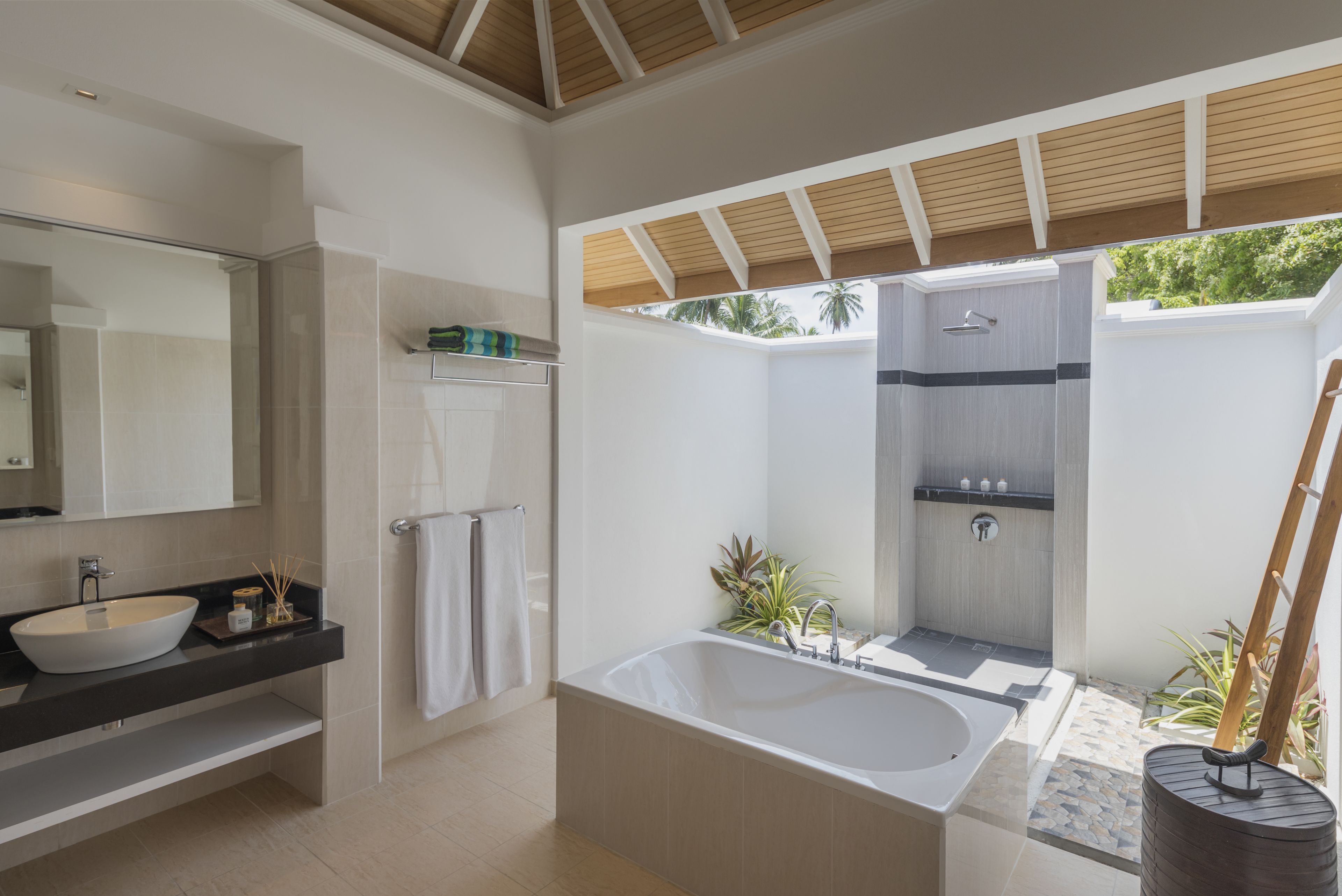 A modern bathroom with a large bathtub, a separate shower area, and a vanity with a sink and mirror.
