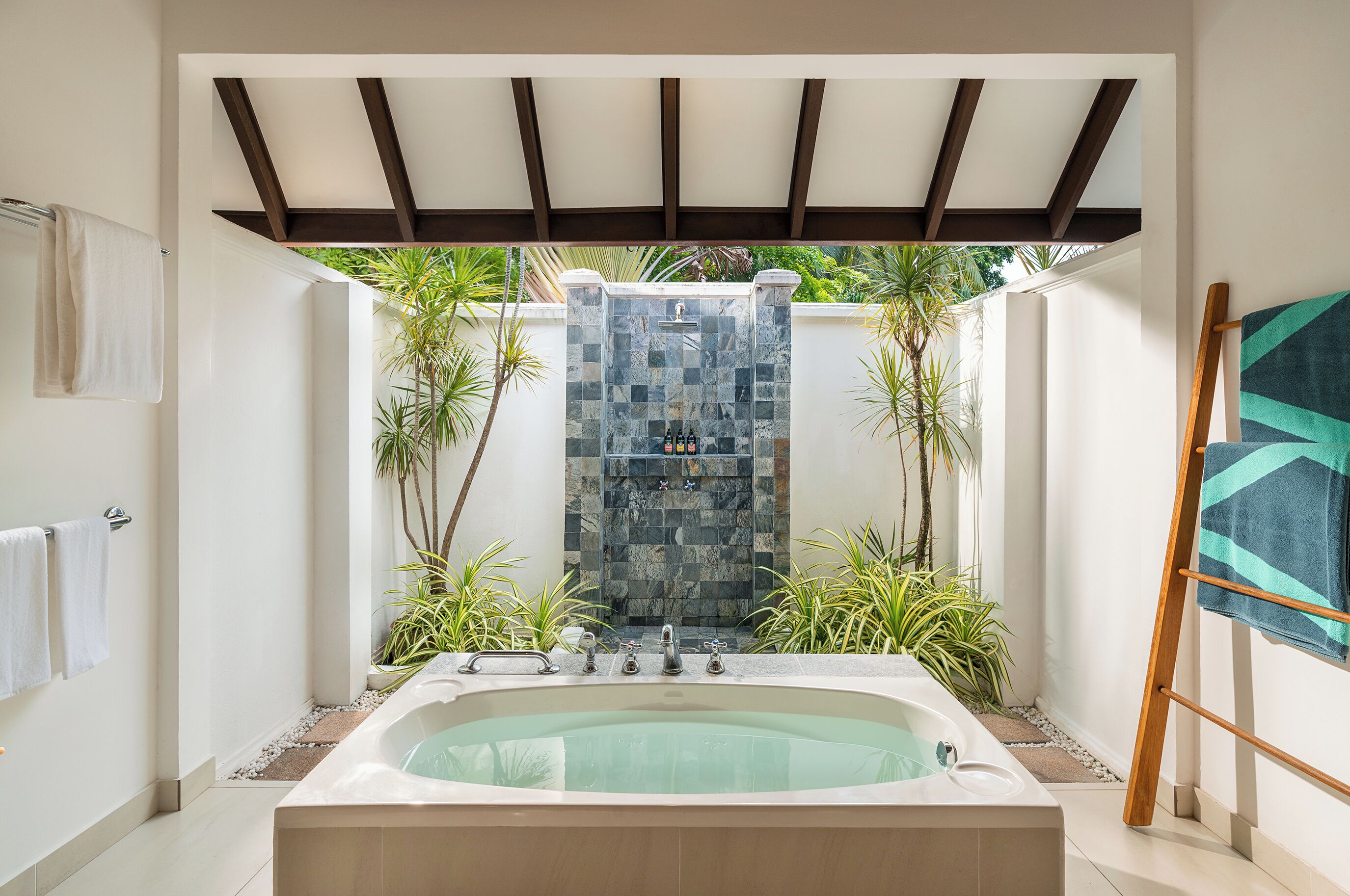 Uma área de spa com hidromassagem, uma cascata de pedra e plantas em vasos.