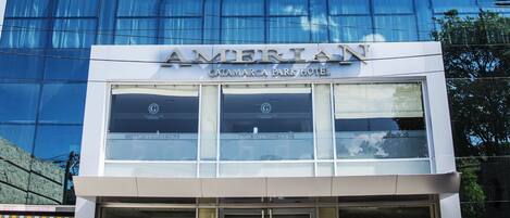 Un hôtel moderne avec une façade en verre et une enseigne indiquant « AMERICAN CATAMARCA PARK HOTEL ».