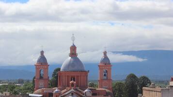 A church with two bell towers and a large dome, surrounded by mountains and clouds.