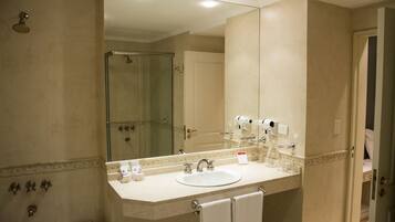A bathroom with a large mirror, a sink, a shower, and a toilet.