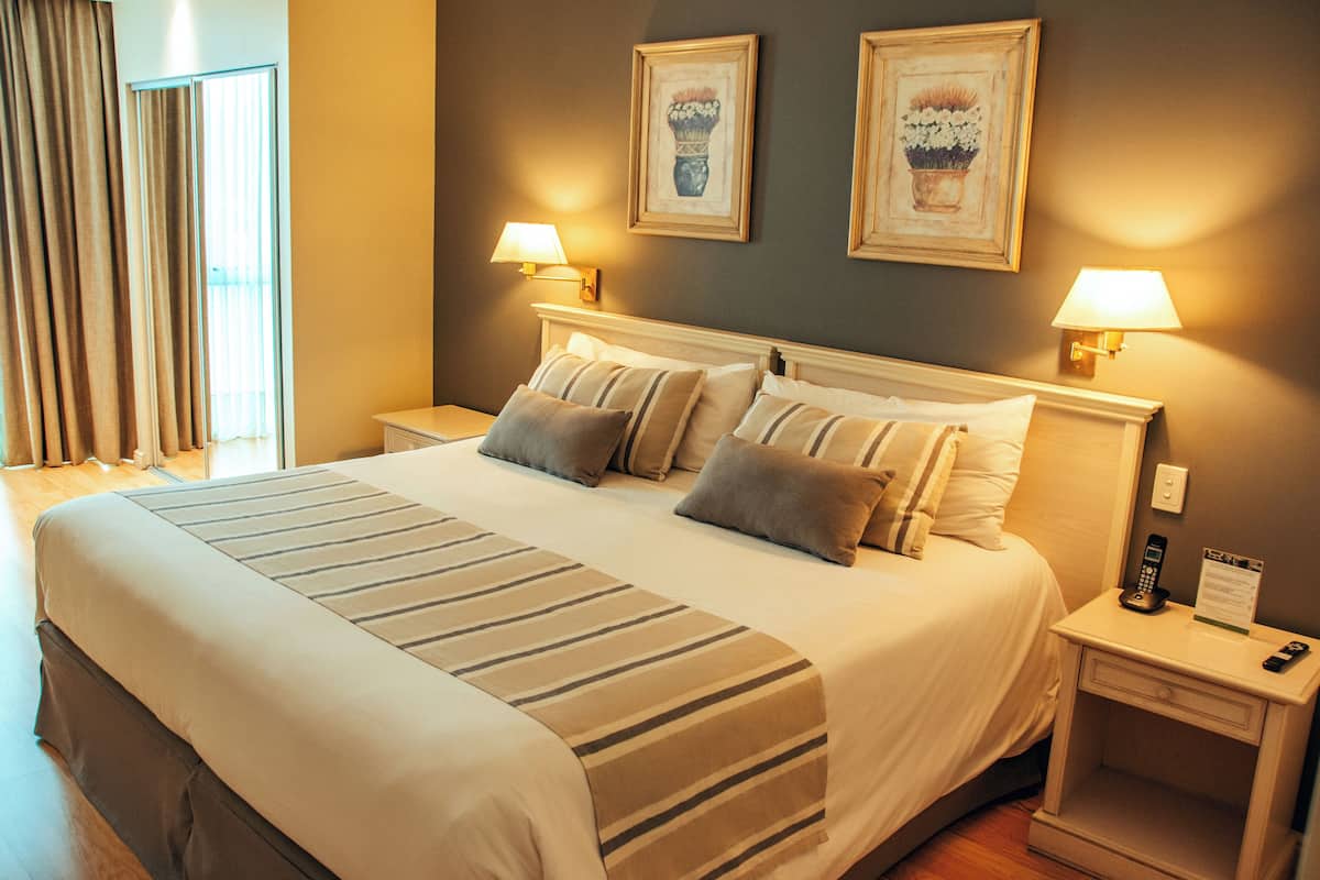 Ein Hotelzimmer mit einem großen Bett, zwei Nachttischlampen und zwei gerahmten Bildern an der Wand.