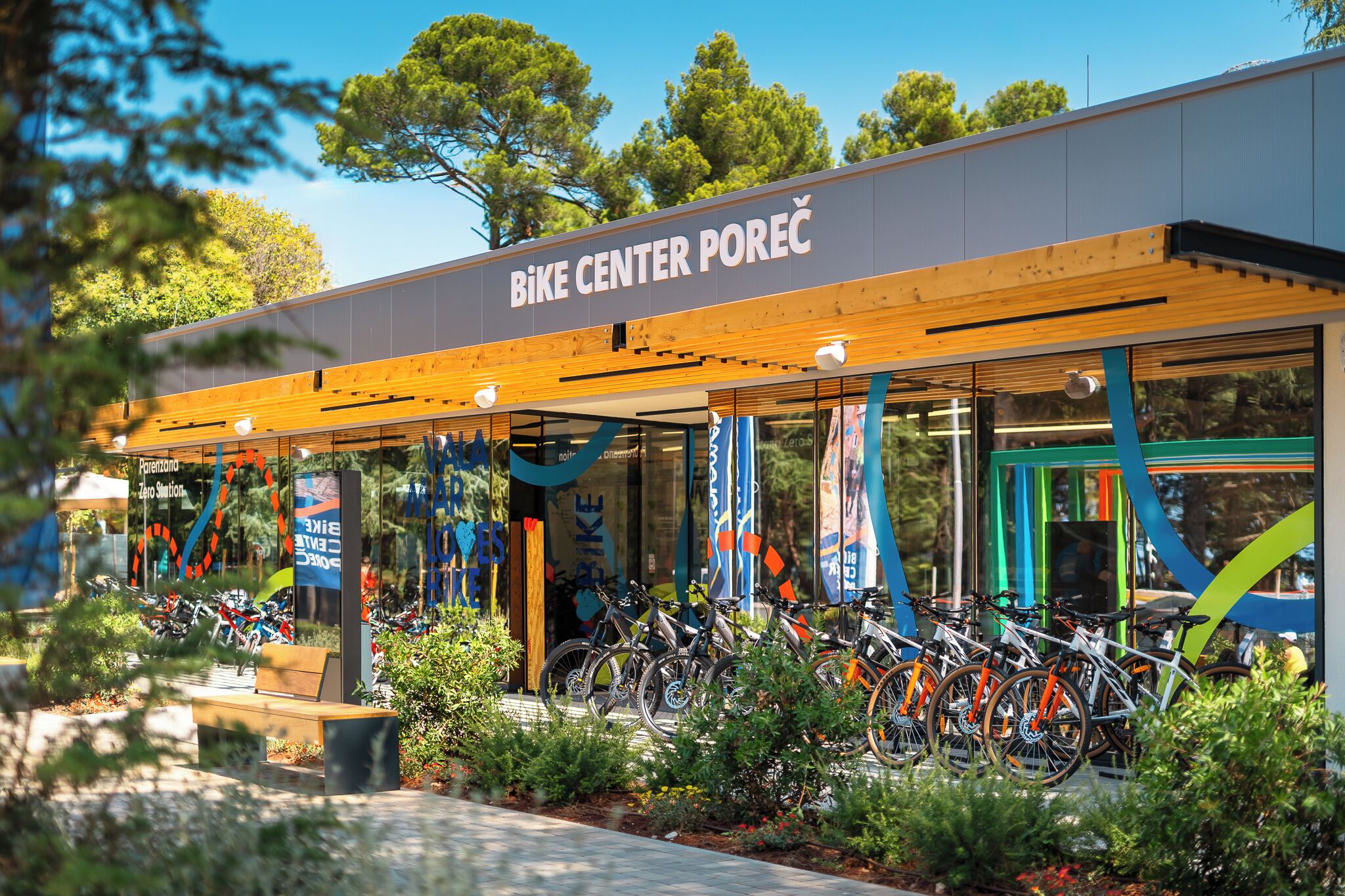 Centro de bicicletas con diseño moderno, que cuenta con una entrada cubierta y una fila de bicicletas estacionadas afuera.