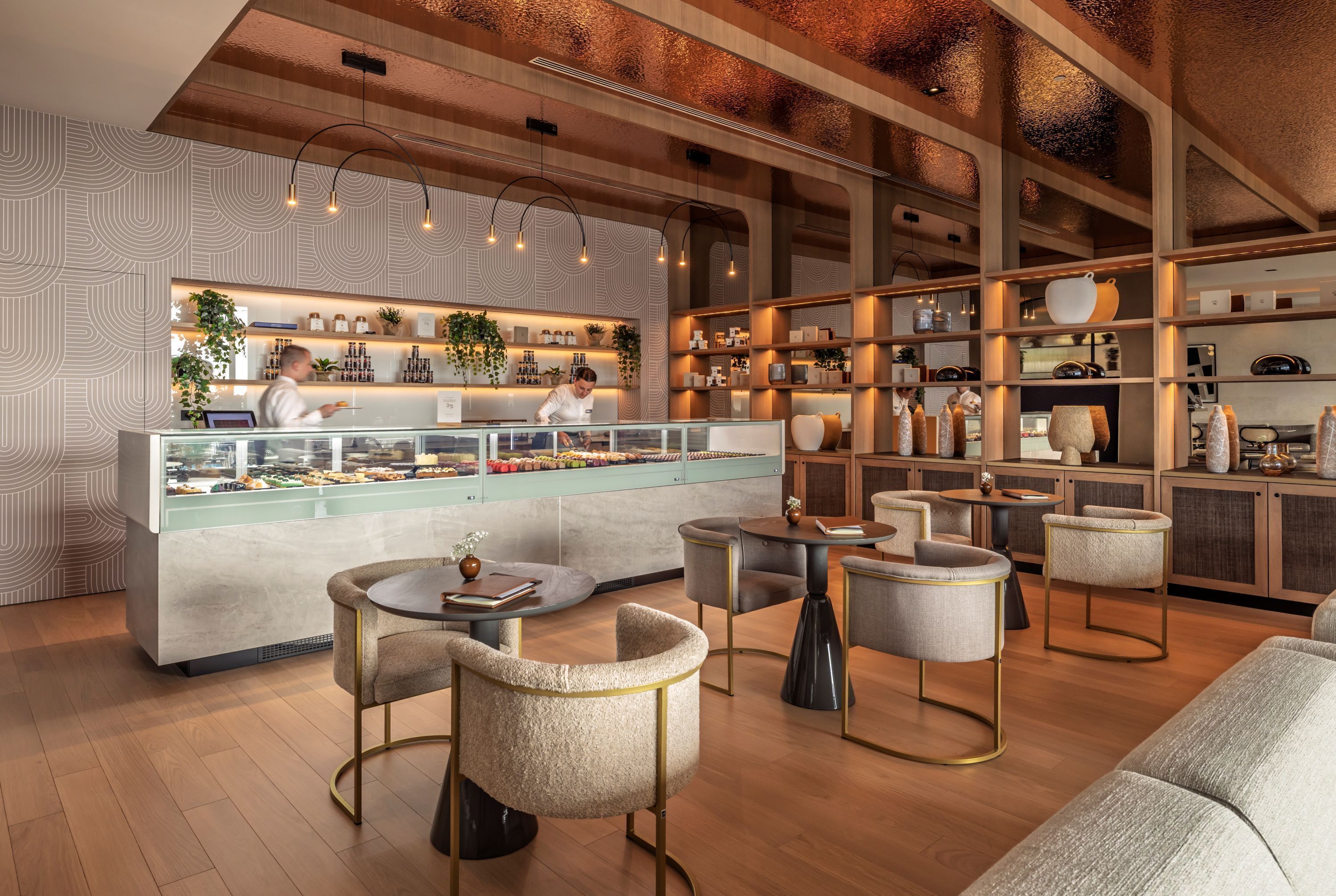A modern cafe with a counter, seating area, and shelves with items.