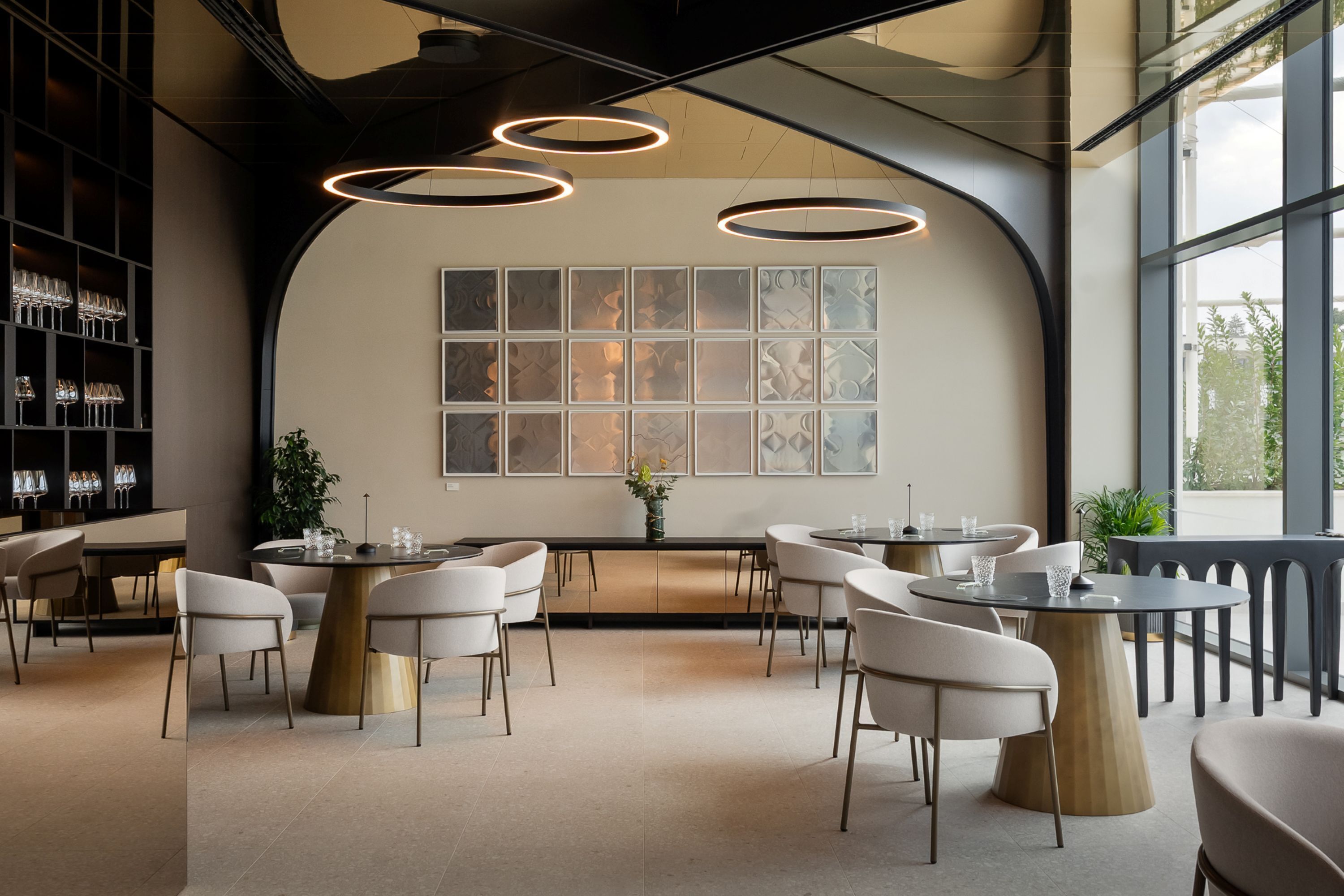 A modern interior with round tables, white chairs, and a large window with a view.