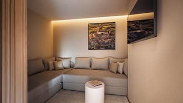 A modern living room with a sectional sofa, a white side table, and a framed landscape painting on the wall.