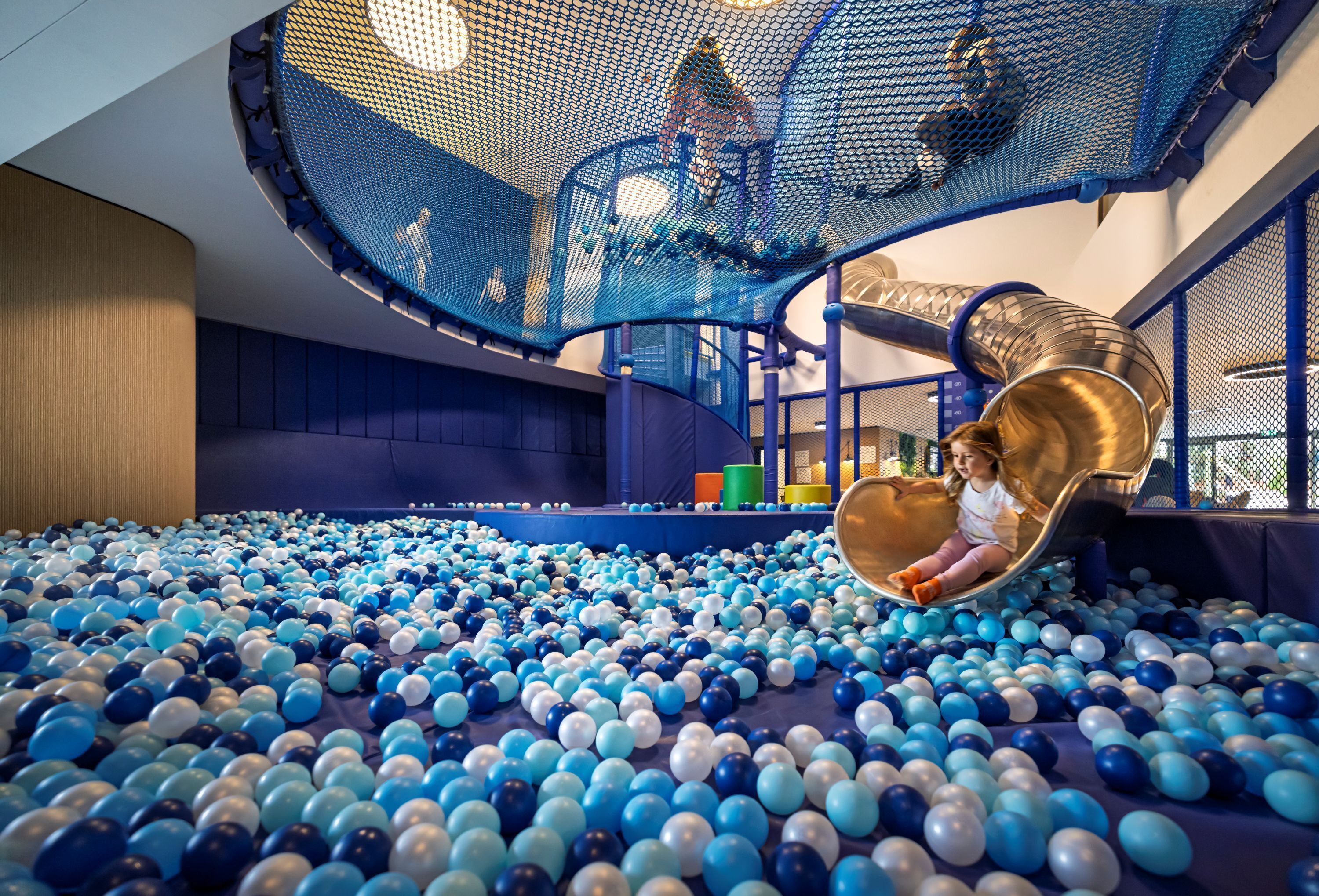 A play area with a ball pit, a slide, and netted climbing structures.