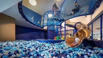 A play area with a ball pit, a slide, and netted climbing structures.