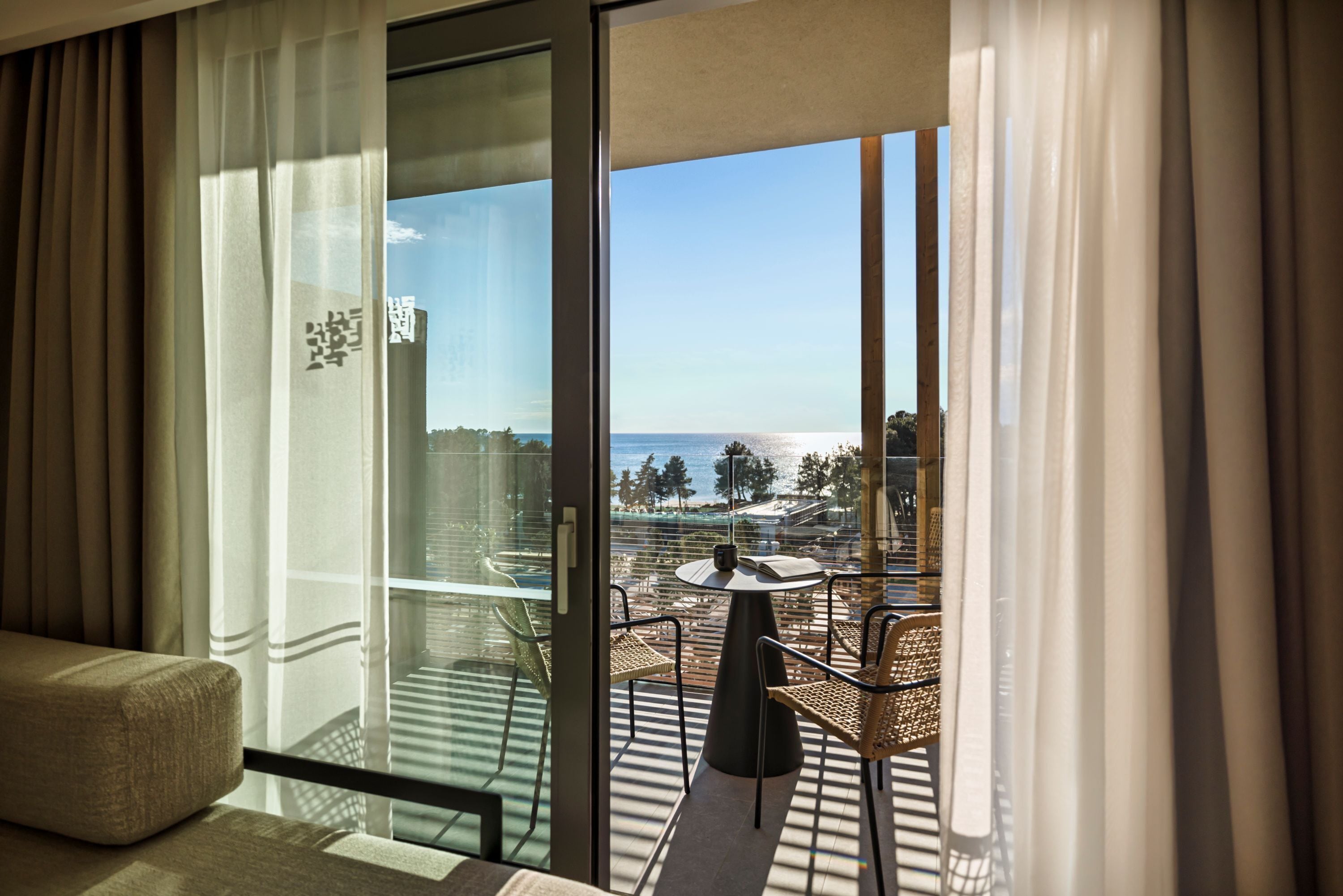 Een balkon met uitzicht op zee, een bank en een tafel met stoelen.
