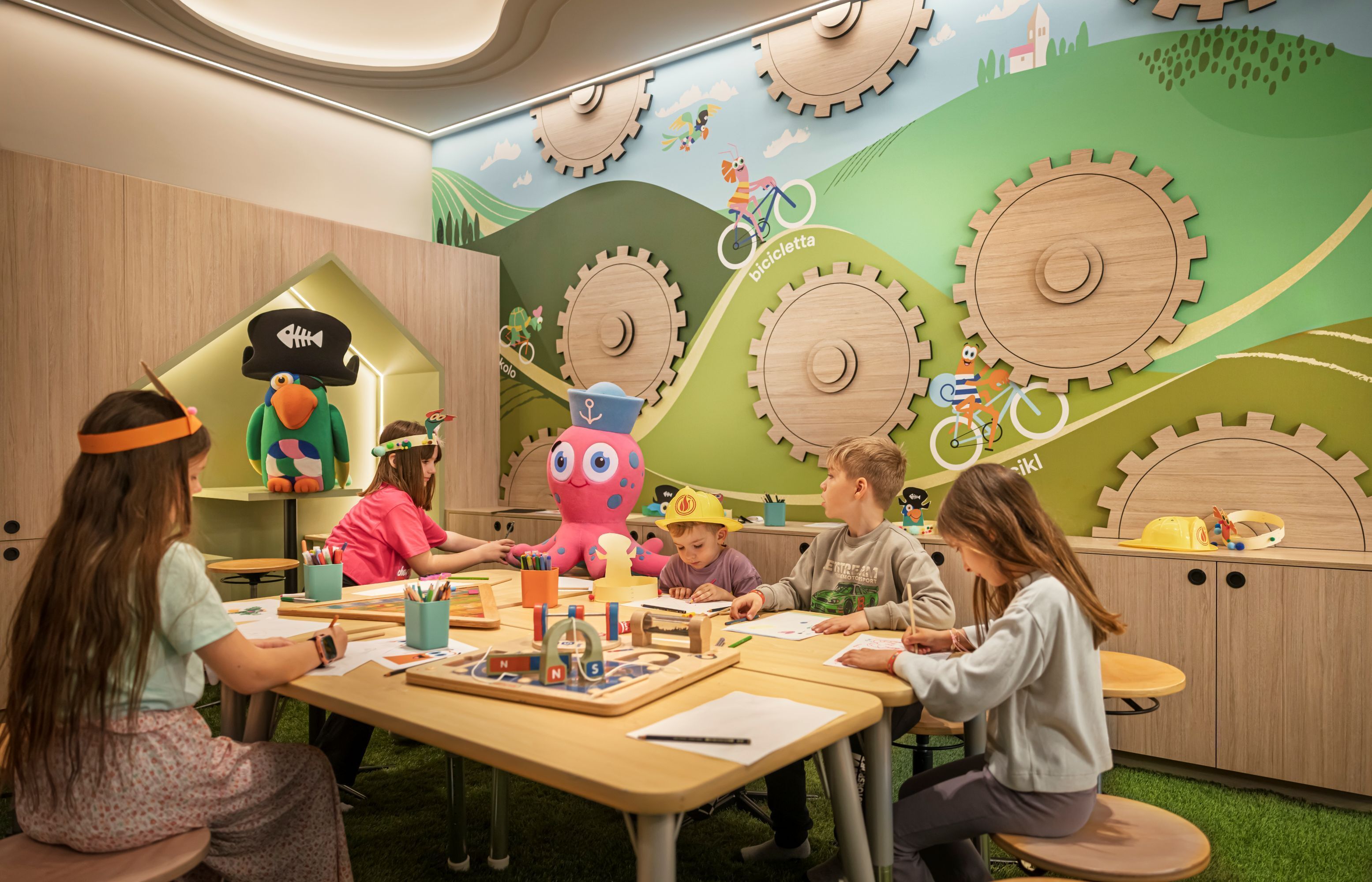 A children's playroom with educational toys, a large octopus decoration, and a wall with gears and bicycles.