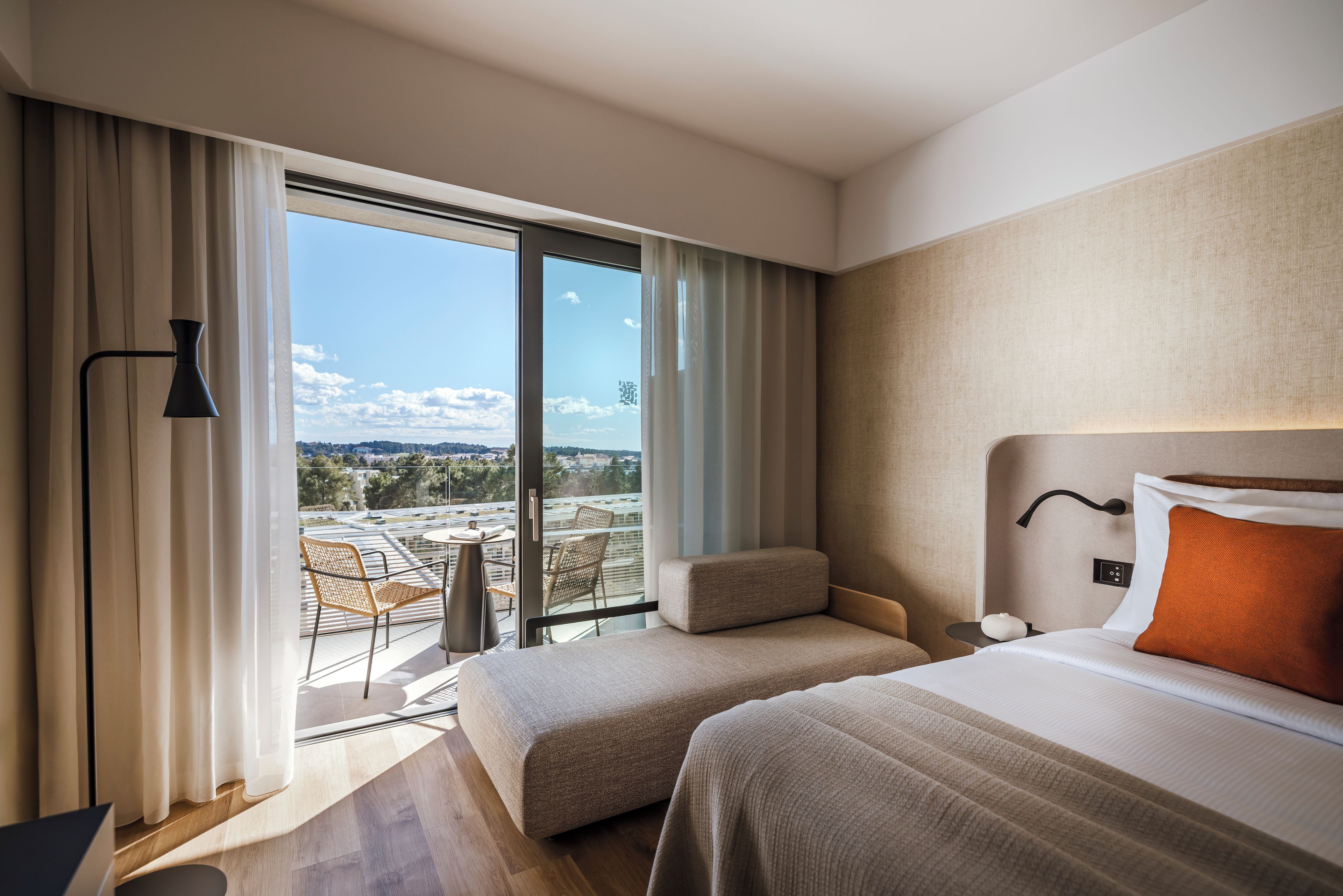 Una habitación de hotel con balcón, una cama, una silla y una mesa.