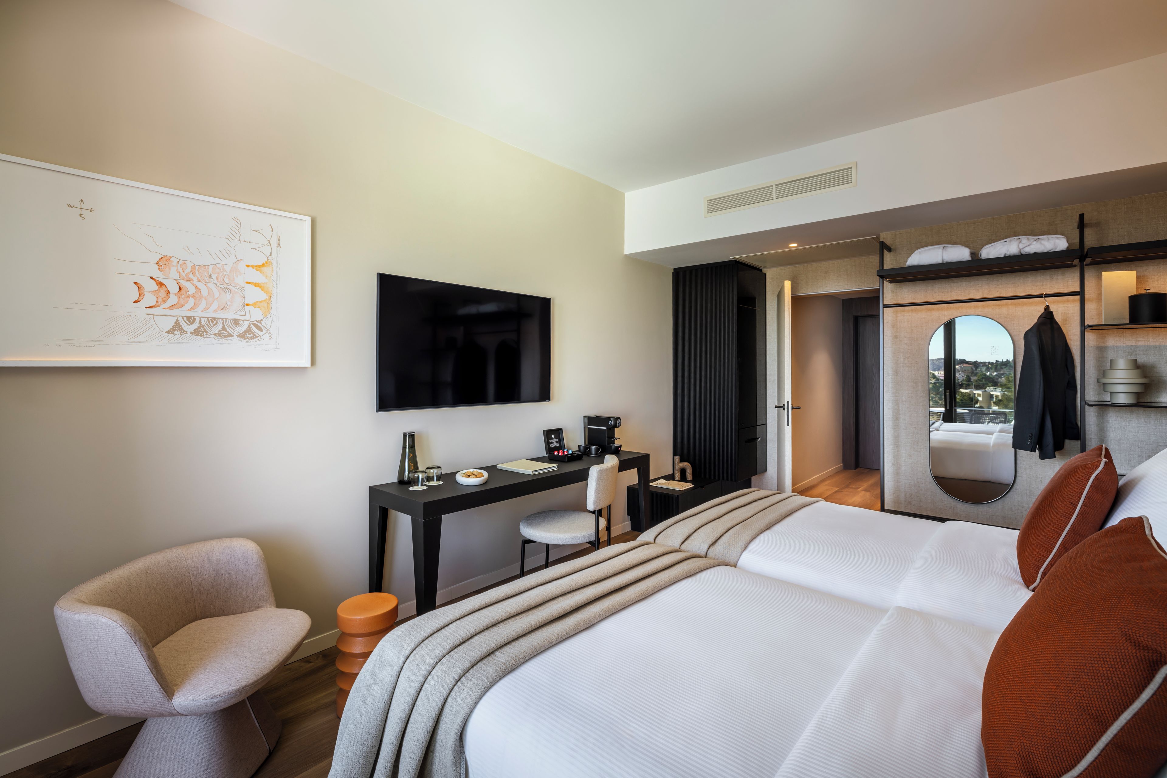 Ein modernes Hotelzimmer mit Bett, Schreibtisch, Stuhl, Flachbildfernseher und großem Fenster.