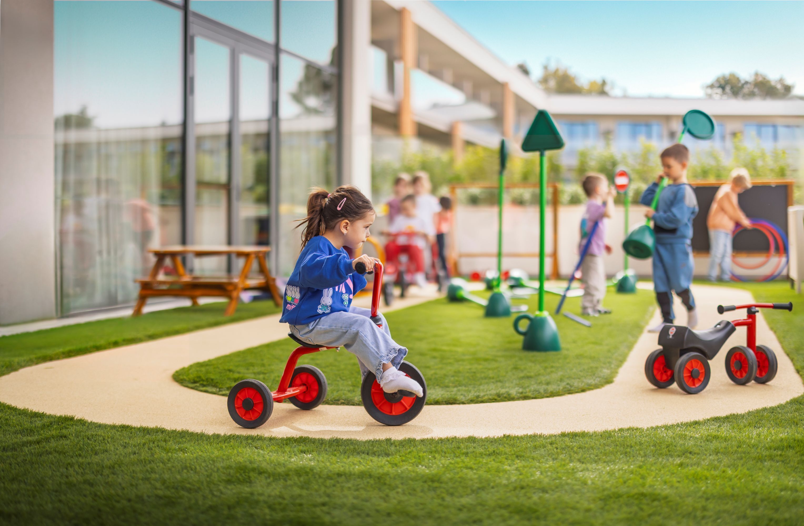 Niños jugando en un parque infantil con un edificio moderno al fondo.