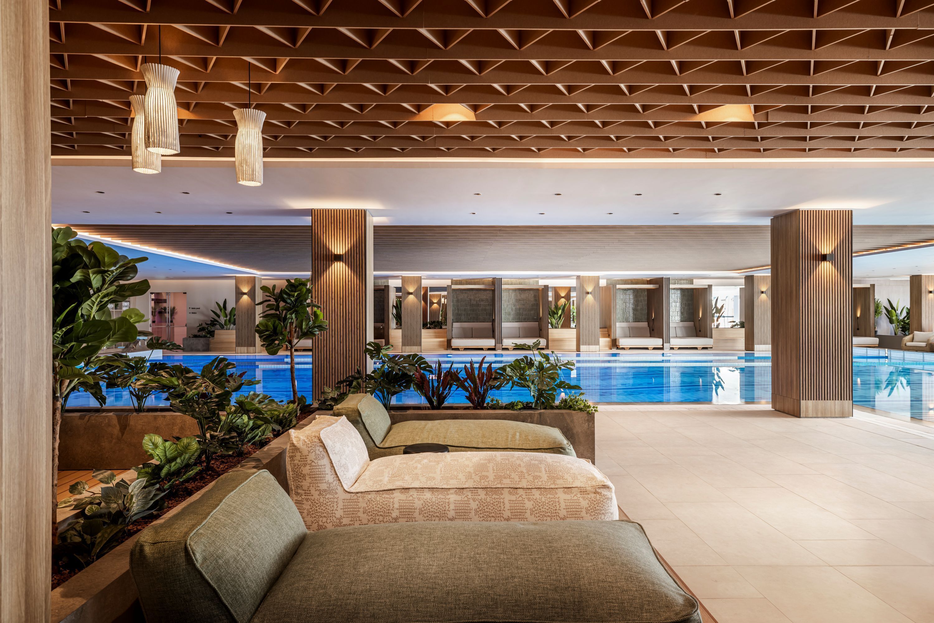 A modern indoor pool area with seating and plants.