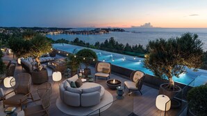 A rooftop terrace with a pool, outdoor seating, and a view of the sea at dusk. - Pical Resort , Valamar  Collection  (Porec)
