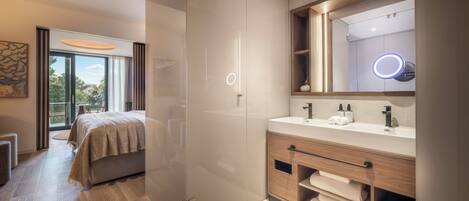 A modern bathroom with a large mirror, a vanity with a built-in sink, and a shower area.