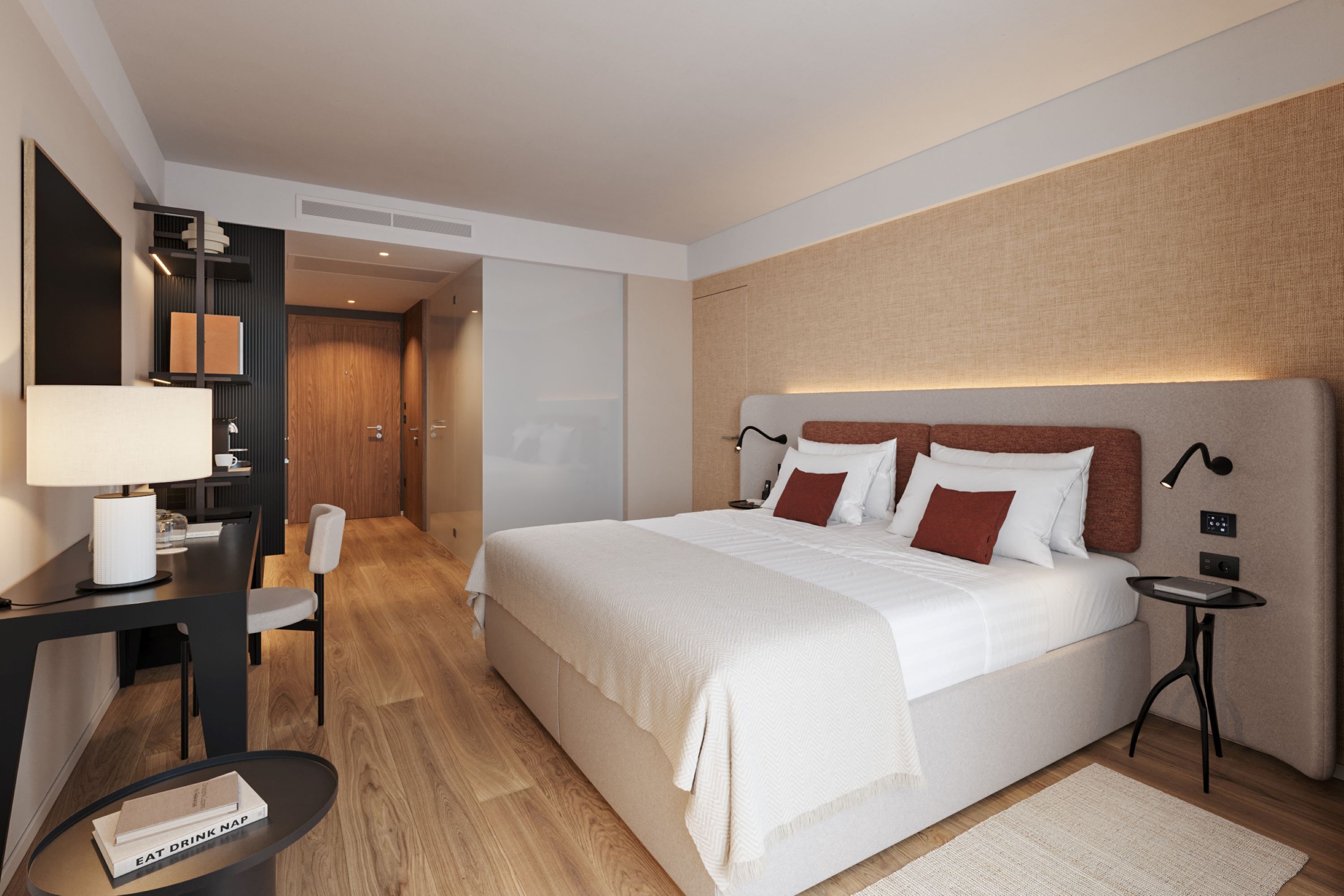 A modern hotel room with a large bed, a desk with a lamp, a chair, and a small table with a book.