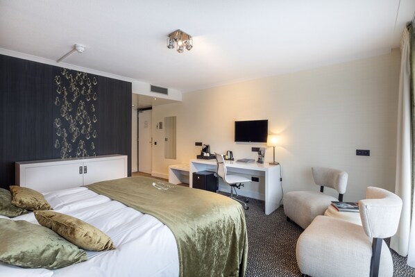 Una habitación de hotel con cama, escritorio, silla, televisor y armario.