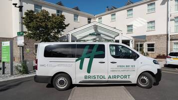 A white van parked in front of a building with a sign for Bristol Airport.