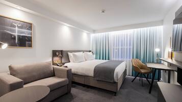 Una habitación de hotel moderna con una cama, un sofá, un escritorio y una silla.