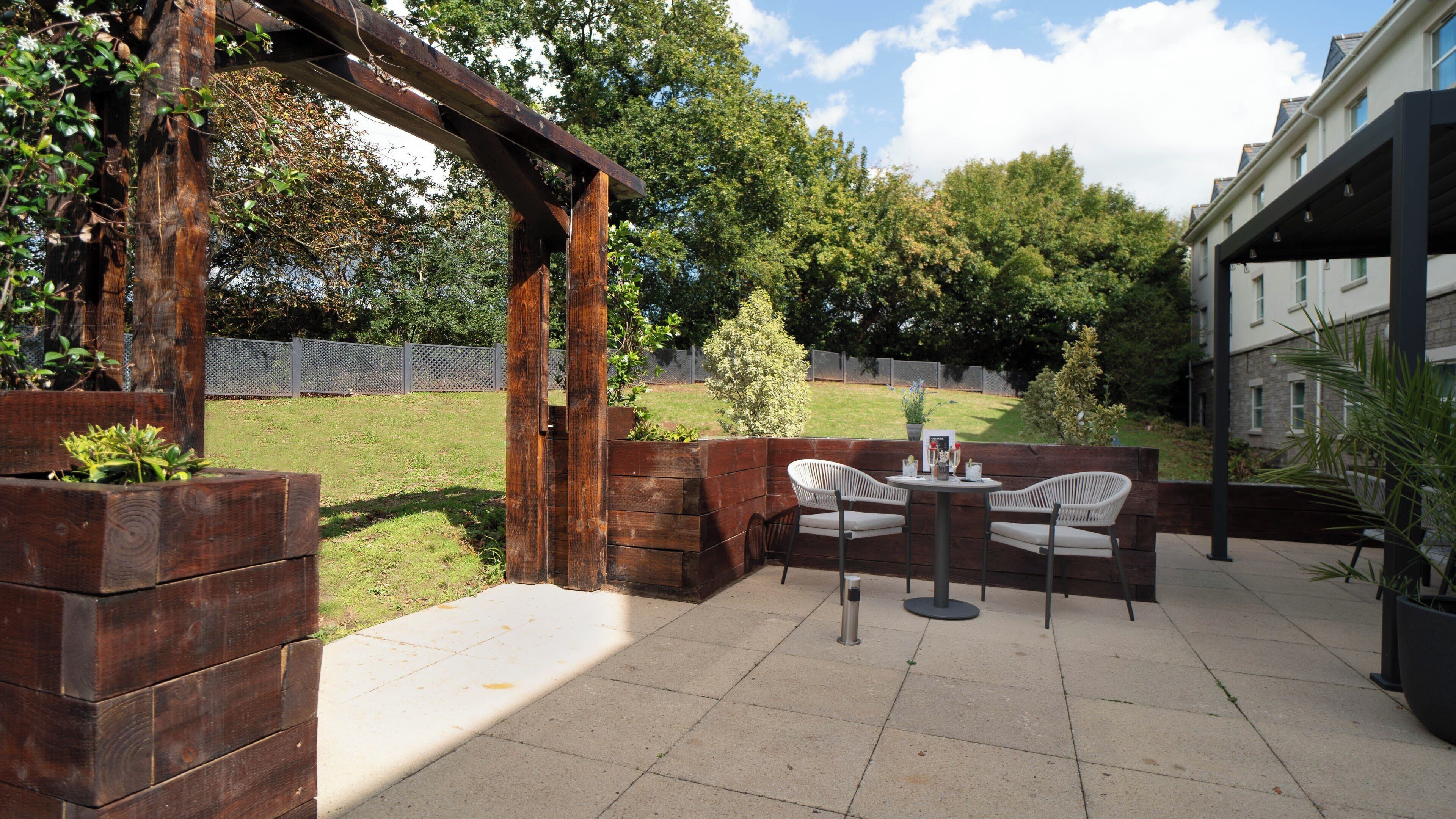 A patio with wooden planters, a pergola, and outdoor seating.