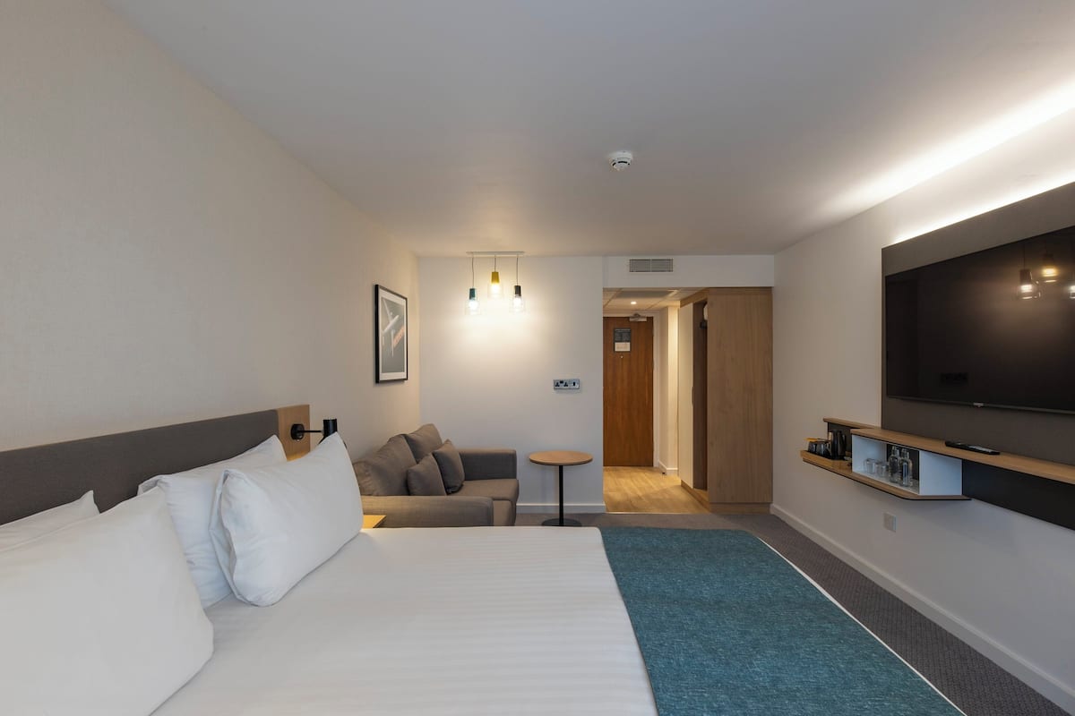 A hotel room with a bed, a sofa, a TV, and a small table.