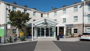 A Holiday Inn hotel entrance with a glass facade, a reception area, and a parking lot. - Holiday Inn Bristol Airport by IHG (Bristol)