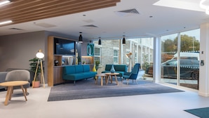 A modern interior with a sofa, chairs, a coffee table, and a bookshelf. - Holiday Inn Bristol Airport by IHG (Bristol)