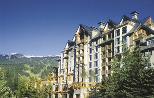 Un hotel de varios pisos con balcones, con montañas al fondo.