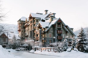 A multi-story hotel with a traditional architectural style, featuring balconies and a stone facade. - Pan Pacific Whistler Village Centre (Whistler)