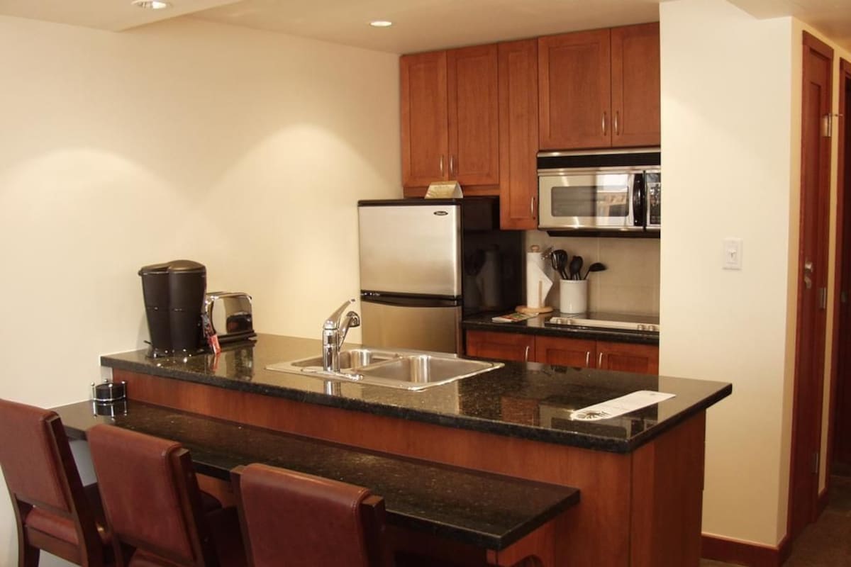 A compact kitchen with a central island, stainless steel appliances, and wooden cabinetry.