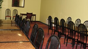 A conference room with a long table and multiple chairs, a small table, and a mirror on the wall. - Best Inn Booneville (Booneville)
