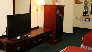 A hotel room with a flat-screen TV on a wooden dresser, a microwave, a lamp, and a small table with a coffee maker. - Best Inn Booneville (Booneville)