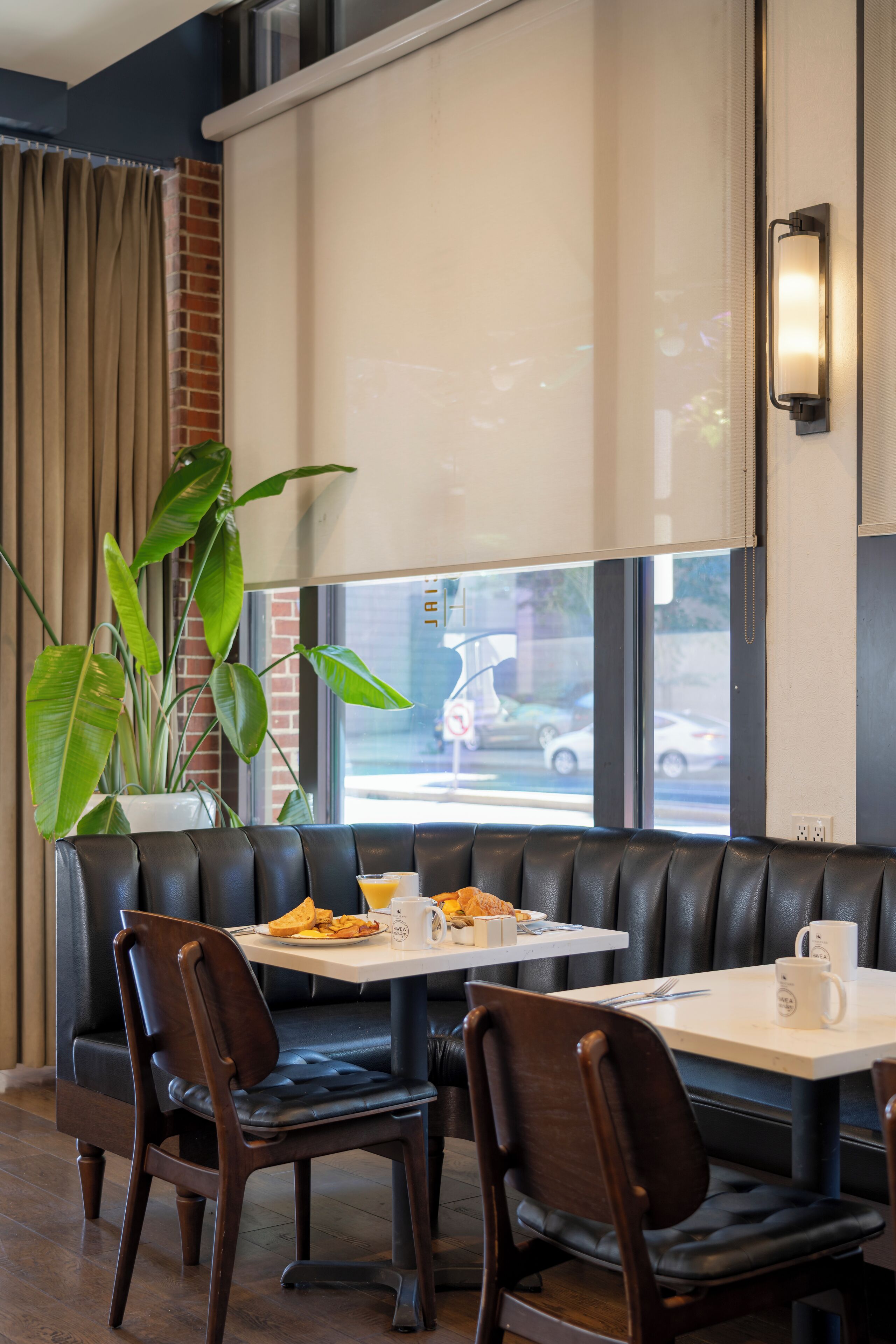 A restaurant with a booth seating area, a table with a white tablecloth, and a large window with curtains.