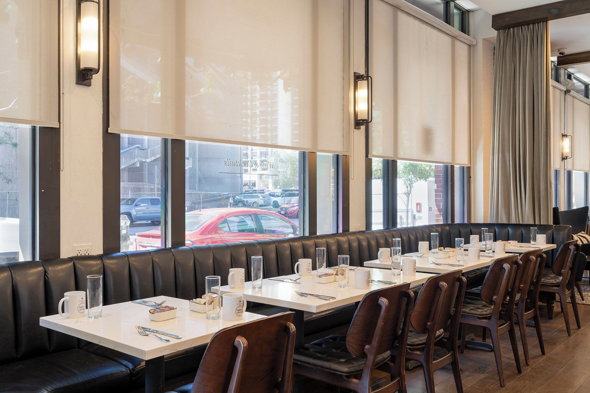 Un restaurante con una barra larga, cabinas de cuero y ventanas amplias.