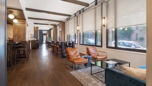 A modern interior with a long corridor leading to a seating area with leather chairs and a table, large windows with city views, and a wooden floor. - Eurostars The Boxer (Boston)