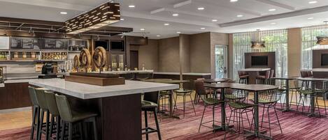 A modern hotel lobby with a bar area, seating arrangements, and large windows.