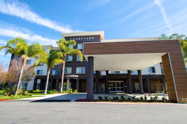 A Courtyard by Marriott hotel entrance with a covered walkway, palm trees, and a clear blue sky. - Courtyard by Marriott Ventura Simi Valley (Simi Valley)