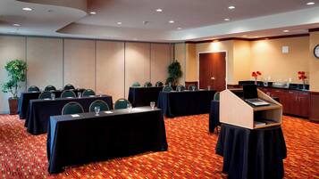 A conference room with tables, chairs, a podium, and a clock on the wall.