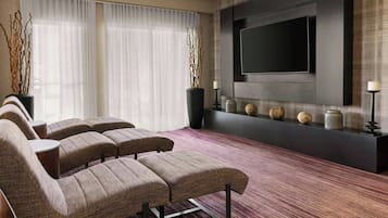 Un salon moderne avec un téléviseur à écran plat fixé au mur, un ensemble de canapés et des objets décoratifs disposés sur une console.
