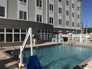 A swimming pool with a lifeguard stand, a white fence, and a building with multiple windows in the background. - Holiday Inn Express Hotel & Suites Orlando South-Davenport by IHG (Davenport)
