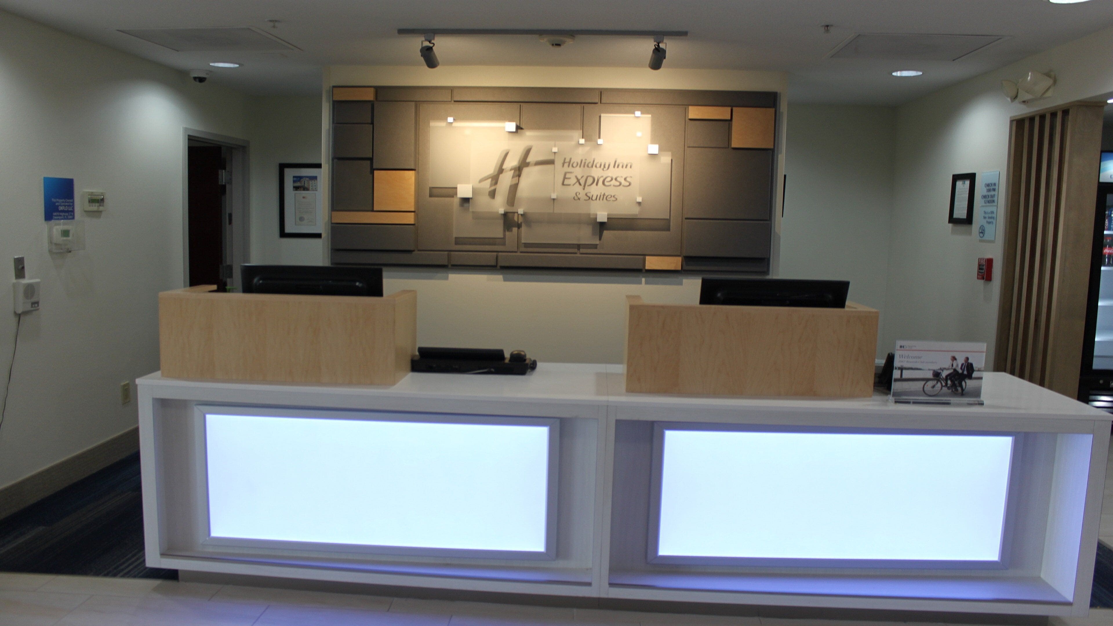 A reception desk with a Holiday Inn Express sign above, two wooden counters, and a digital display.