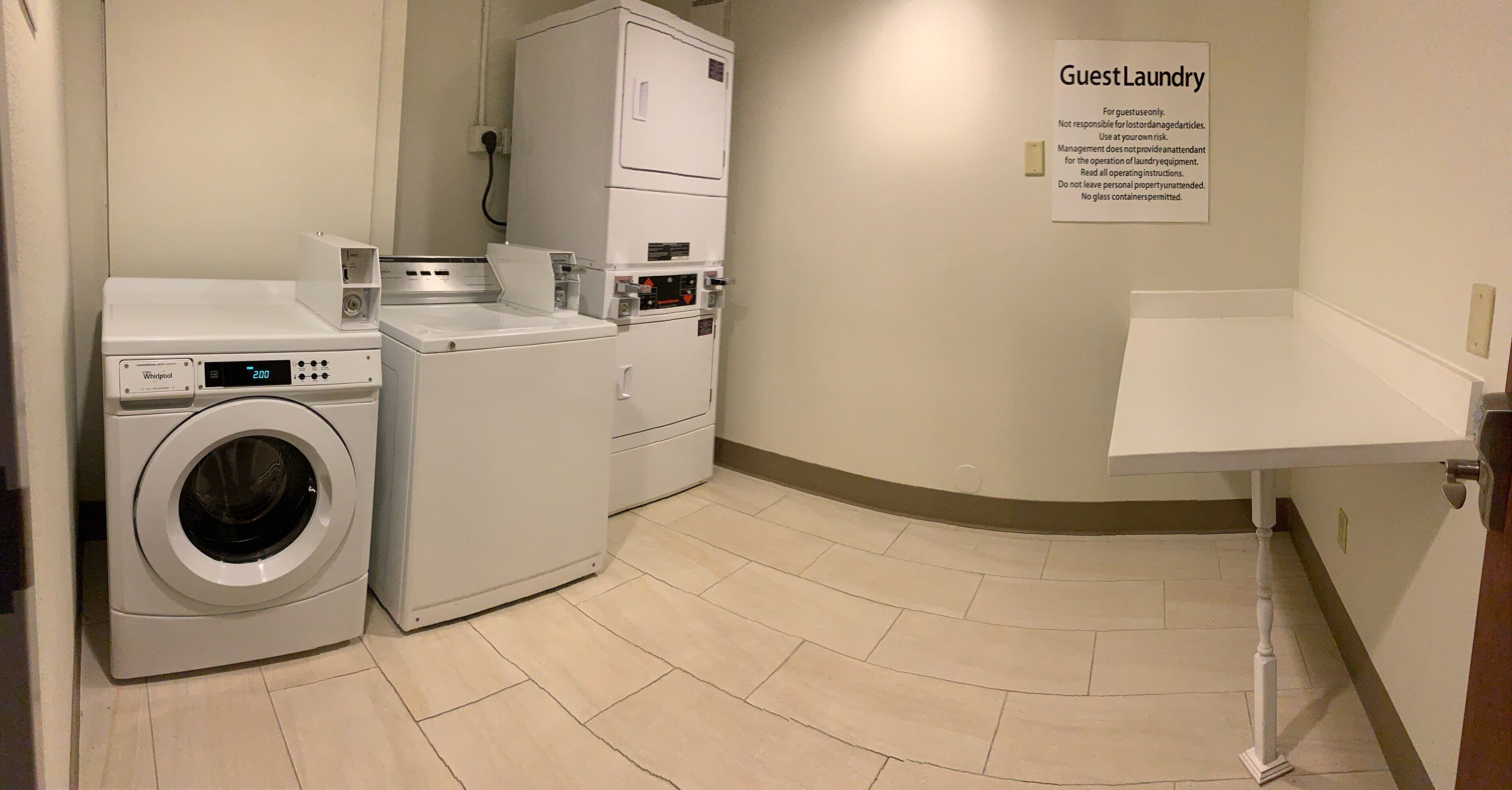 A laundry room with a Whirlpool washer, a dryer, and a sign indicating it's for guest use.
