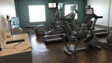 A gym with multiple treadmills, a water dispenser, and a mirror reflecting the room.
