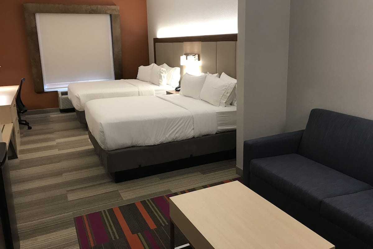 Ett hotellrum med två sängar, ett skrivbord, en stol, en soffa och en TV.