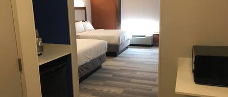 A hotel room with two beds, a TV, and a window with blinds.