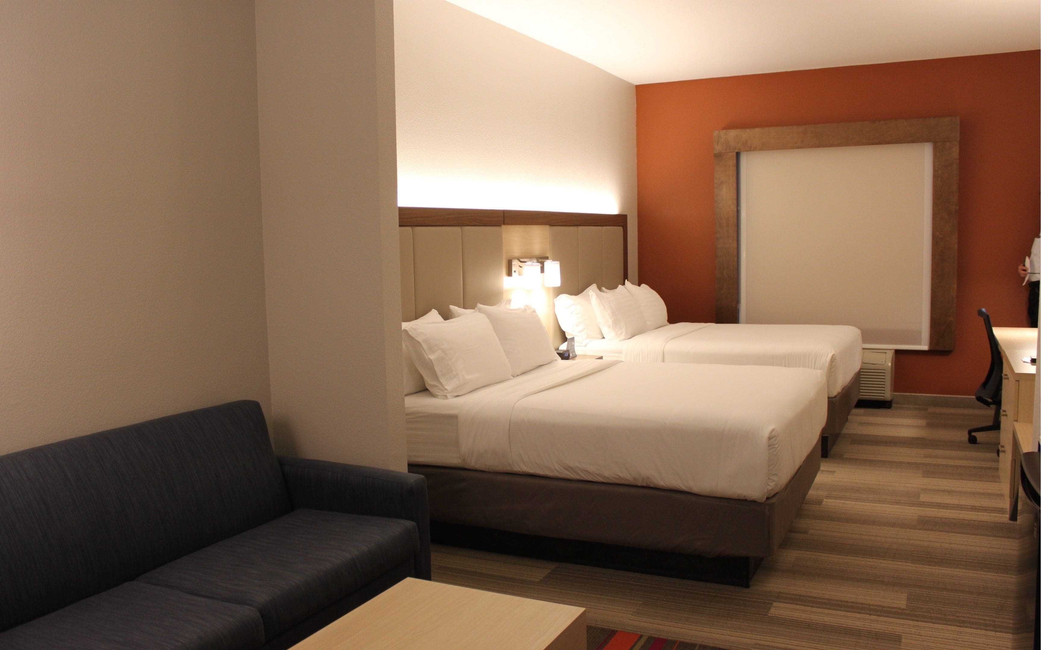 Une chambre d’hôtel avec deux lits, un canapé, un bureau et une grande fenêtre.