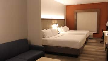 Une chambre d’hôtel avec deux lits, un canapé, un bureau et une grande fenêtre.