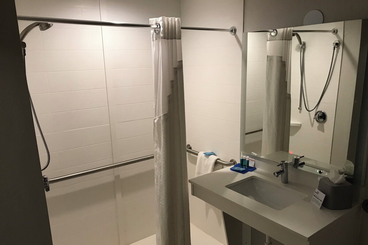 A bathroom with a shower, a sink, and a mirror.